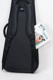 A black padded carrying case or bag with shoulder straps, shown upright against a light gray studio background. A magazine or booklet is tucked into one side pocket.