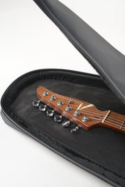 A close-up of a guitar headstock resting inside an open black zippered hard case with a padded black interior, photographed on a clean white background.