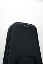 Close-up of a black textured instrument case or hardshell bag with a metal D-ring near the top, photographed against a plain white background.